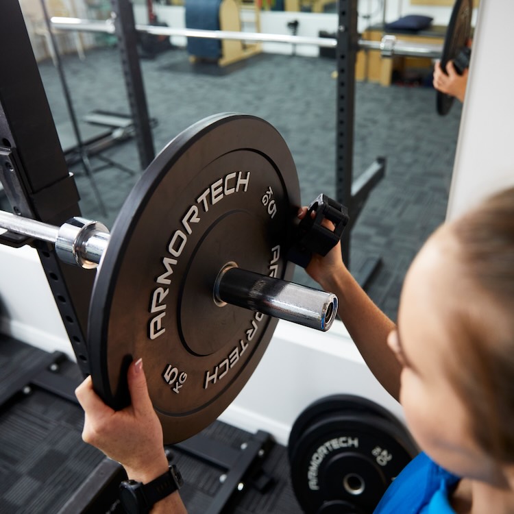 Amy racking weights to prepare for a sports physio appointment in Fremantle